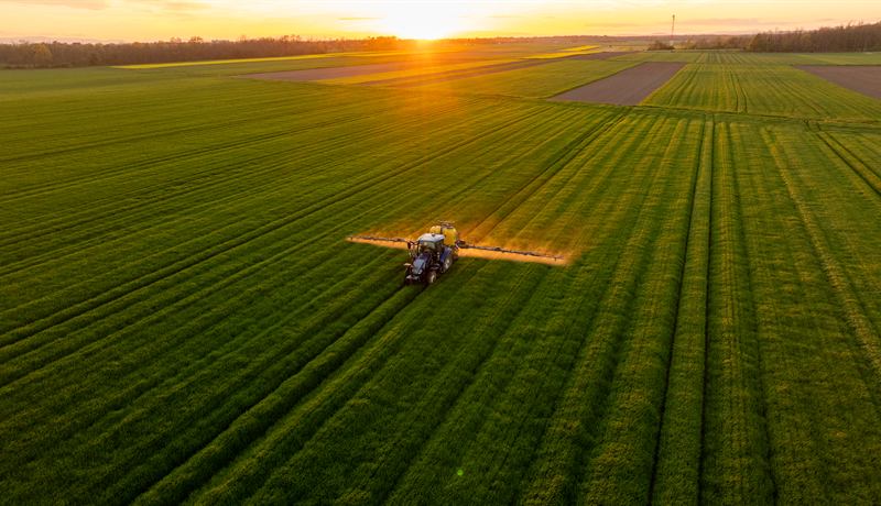 Aerial view of a sprayer applying crop protection across a green field